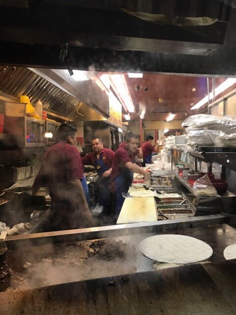 El Farolito kitchen crew working the grill with steam rising from fresh tortillas