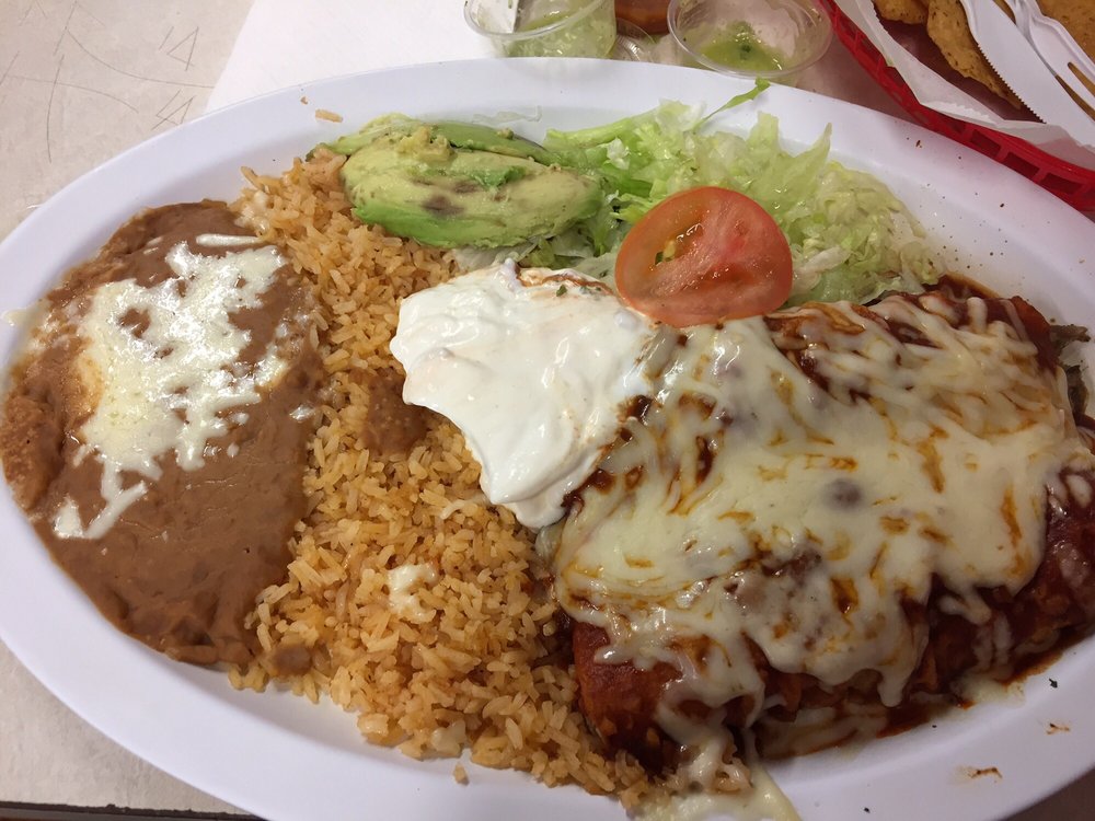 Enchiladas plate with rice, refried beans, sour cream, avocado, and melted cheese