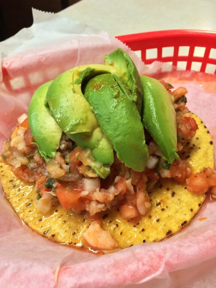 Shrimp tostada with fresh avocado slices, ceviche, and pico de gallo on a crispy tortilla